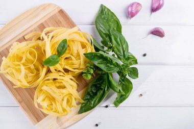 Düz yatıyordu. Pişmemiş makarna ve sarımsaklı beyaz masada yeşil taze fesleğen