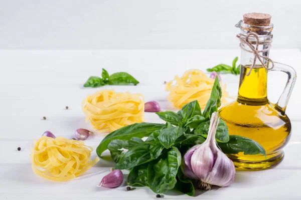 Basilico verde fresco con aglio, olio d'oliva e pasta cruda su tavola bianca — Foto Stock