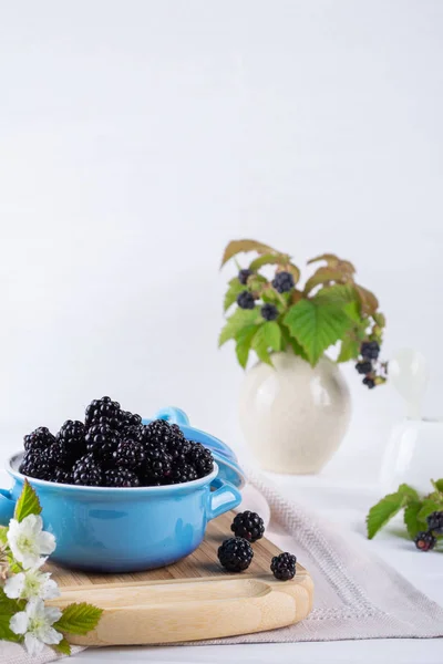 Composition of branch of Blackberry with leaf and  blackberries in a blue ceramic bowl on white table. — Stock Photo, Image