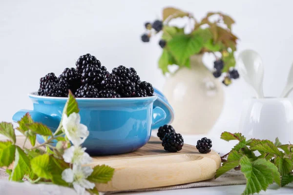 Composition of branch of Blackberry with leaf and  blackberries in a blue ceramic bowl on white table. — Stock Photo, Image