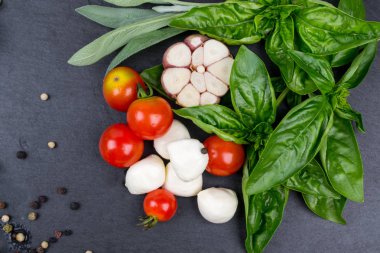 Mozzarella peyniri, domates ve taze fesleğen, limon, sarımsak. Salata için malzemeler. Kara kayrak taş üzerine. Üstten Görünüm.