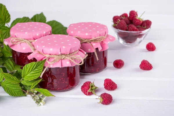 Raspberry jam in glass jar, fresh  ripe raspberry and green leaves — Stock Photo, Image