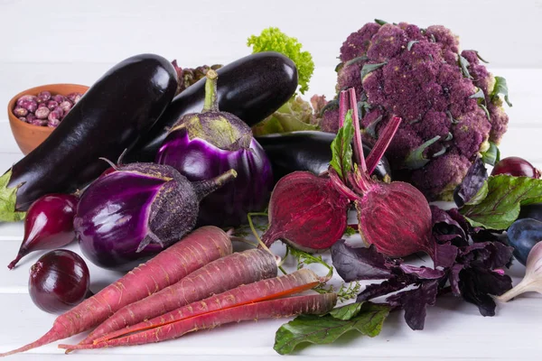 Asortyment świeżych surowych warzyw fioletowy na biały stół — Zdjęcie stockowe
