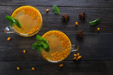 Deniz topalak cam bardak taze çiğ deniz cehri çilek ve tarçın, anason yıldız ve ballı bir karanlık mutfak masasında ile baharatlı sıcak içecek.