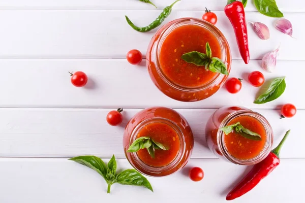 Salsa de tomate ketchup con tomates cherry y chiles rojos picantes, ajo y hierbas en un frasco de vidrio — Foto de Stock