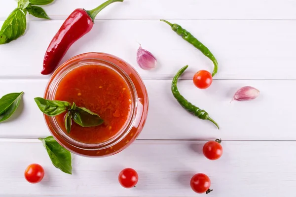 Salsa de tomate ketchup con tomates cherry y chiles rojos picantes, ajo y hierbas en un frasco de vidrio — Foto de Stock