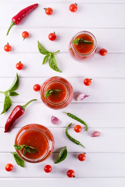 Salsa de tomate ketchup con tomates cherry y chiles rojos picantes, ajo y hierbas en un frasco de vidrio — Foto de Stock