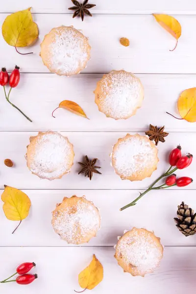 Flat lay em estilo outono. Deliciosos cupcakes com paus de canela, estrelas de anis, bagas de rosa mosqueta e folhas de outono — Fotografia de Stock