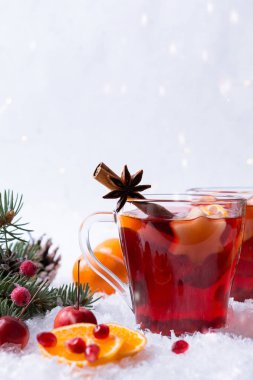 Sıcak sıcak baharatlı kırmızı şarap cam kupa ile şenlikli dekorasyon ışıklar ve gingerbread ile. Beyaz kar arka plan üzerinde