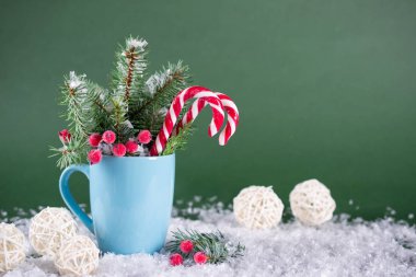 Noel ve yeni yıl kartı. Çam ağaçları, baston şekerler ile fincan. Yeşil parlak arka plan üzerinde.