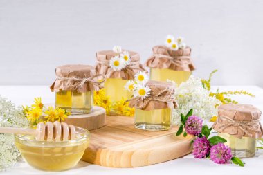 Doğal ışık sıvı bal. Cam Kavanoz ve çiçekli beyaz arka plan üzerinde Kepçe tatlım.