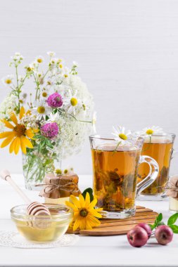  Bitki çayı, bir kavanoz bal ve kır çiçekleri sağlıklı bir fincan. Beyaz arka plan üzerinde