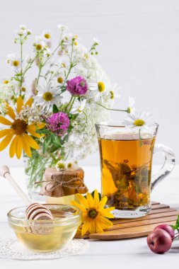 Bitkisel Çay otlar ve bal ile cam çaydanlık çiçeklenir. Beyaz masaya çiçek buketi