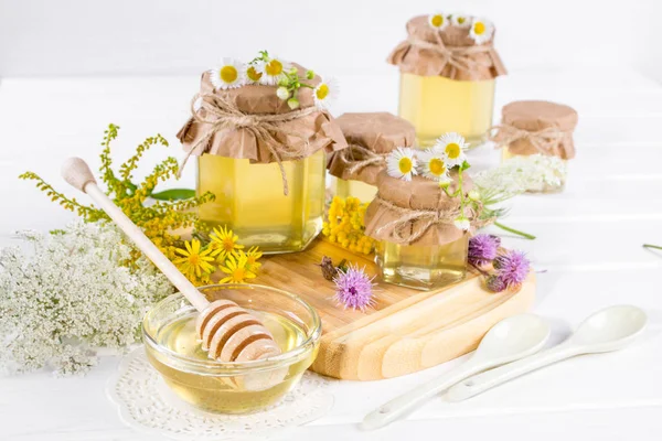 Honey in a jar, flowers and honey dipper on white background