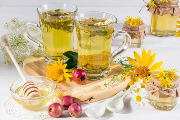 Cup of herbal tea with natural light liquid honey  and wild flowers on white background