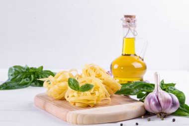 Sarımsak, zeytinyağı ve pişmemiş makarna beyaz zemin üzerine yeşil taze fesleğen. 