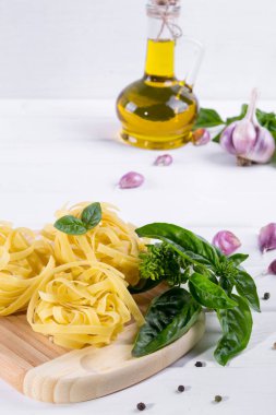 Sarımsak, zeytinyağı ve pişmemiş makarna beyaz zemin üzerine yeşil taze fesleğen. 