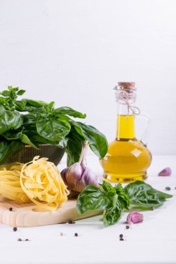 Sarımsak, zeytinyağı ve pişmemiş makarna beyaz zemin üzerine yeşil taze fesleğen. 