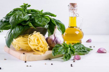 Sarımsak, zeytinyağı ve pişmemiş makarna beyaz zemin üzerine yeşil taze fesleğen. 