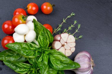 Mozzarella peyniri, domates ve taze fesleğen, limon, sarımsak. Salata için malzemeler. Siyah arduvaz taş tahta. Üstten Görünüm.