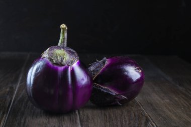 Karanlık rustik ahşap arka plan üzerinde çiğ mor yuvarlak patlıcan. 