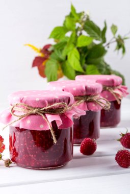 Satırlar ve Beyaz ahşap masa üzerinde taze ahududu Frambuaz reçeli ile kavanoz yerleştirilir