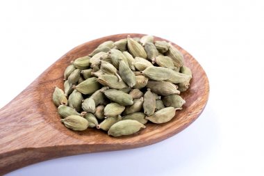 tahta kaşık beyaz arka plan üzerinde izole üzerinde tüm kakule tohumu 