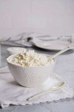 Beyaz bir kase taze sütten peynir. Gri beton zemin üzerine.