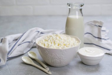 Organik çiftçi taze süt ve süt ürünleri: süt, süzme peynir, ekşi krema. Gri beton zemin üzerine.