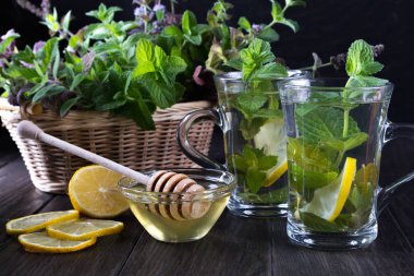 Taze yeşil nane ve iki cam bardak taze nane çayı üzerinde koyu arka plan ile sepet.