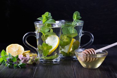 İki cam bardak taze nane çayı .limon ve ballı koyu arka plan üzerinde.