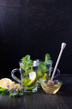 İki cam bardak taze nane çayı .limon ve ballı koyu arka plan üzerinde.