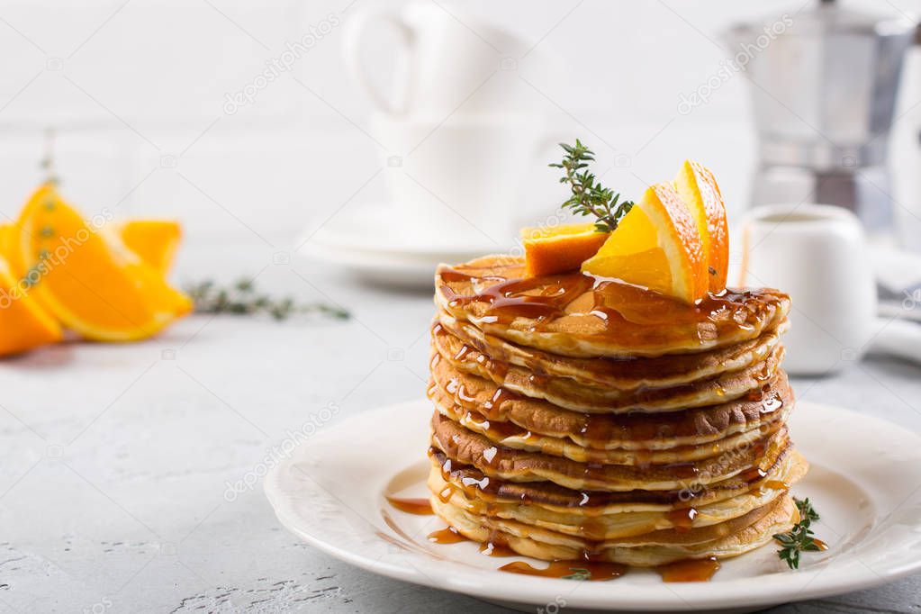 Table of breakfast . Pancakes with orange and sprinkled maple syrup, orange juice and coffee
