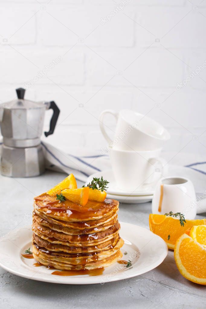 Table of breakfast . Pancakes with orange and sprinkled maple syrup, orange juice and coffee