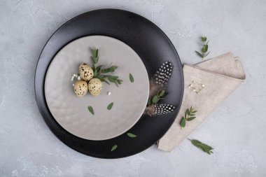 Paskalya Festival tablo ile gri plaka, bıldırcın ayarlama, okaliptüs yaprağı dal yumurta. Bir gri beton zemin üzerinde.