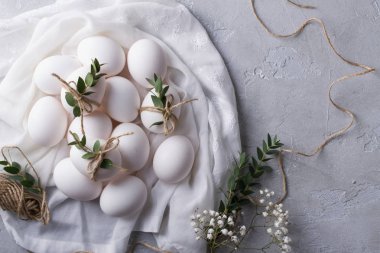 Paskalya kavramı. Beyaz kumaş üzerine beyaz tavuk yumurtası. Okaliptüs yaprakları ile süslenmiş. En iyi görünüm ve kopya alanı.