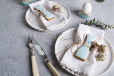 Paskalya Festival tablo Easter bunny Çerezler, ayarıyla Bıldırcın yumurta ve yumurta, yeşil yaprak dal okaliptüs, tavuk. Bir gri beton arka plan üzerinde. Tatil kutlama süslemeleri.