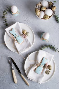 Paskalya Festival tablo Easter bunny Çerezler, ayarıyla Bıldırcın yumurta ve yumurta, yeşil yaprak dal okaliptüs, tavuk. Bir gri beton arka plan üzerinde. Tatil kutlama süslemeleri.