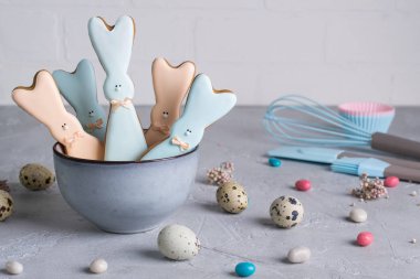 Paskalya bahar dekoratif kompozisyon ile ev yapımı Paskalya kurabiye şeklinde komik tavşan, bıldırcın yumurtası ve zencefilli kurabiye pasta yapmak için gerekli araçları. Bir gri beton arka plan üzerinde. Tatil kutlama süslemeleri.