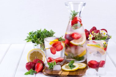 Mineral su beyaz arka planda, ev yapımı Detoks maden suyu tarifi çilek, buz, ot ve nane yaprakları ile infüzyon.
