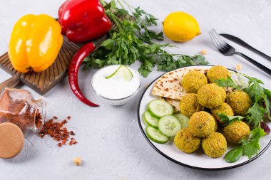 Ev yapımı baharatlı nohut falafel hafif beton arka plan üzerinde taze sebze ve bir tabak yoğurt ile süslenmiş. İsrail mutfağı kavramı