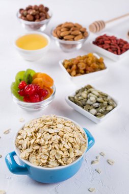 Mavi kapta yulaf gevreği ve çeşitli lezzetli maddeler mutfak masasının üzerinde sağlıklı kahvaltı için. Sağlıklı kahvaltı konsepti.