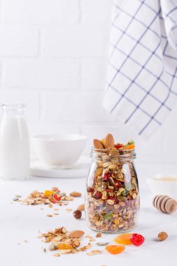 Beyaz arka plan üzerinde pişmiş granola ile cam kavanoz. Yulaf gevreği, tatlım, fındık, Kuru Meyve ve tohumlar. Sağlıklı snak