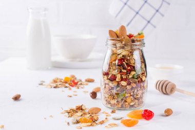 Beyaz arka plan üzerinde pişmiş granola ile cam kavanoz. Yulaf gevreği, tatlım, fındık, Kuru Meyve ve tohumlar. Sağlıklı snak