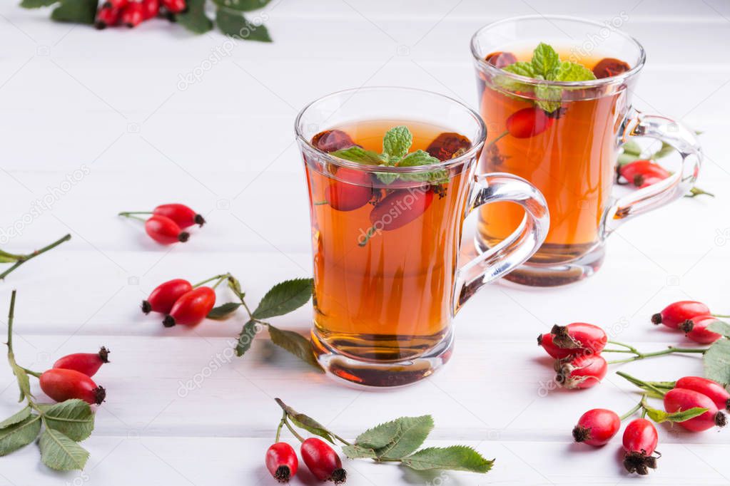 Healthy autumn  tea with dog roses, branch with berries on white  background.