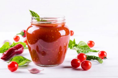 Salça, ketçap cam kavanoz ve malzemelerin üzerine beyaz bir arka plan 