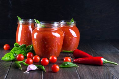 Salça, ketçap cam kavanoz ve malzemelerin koyu arka plan üzerine 