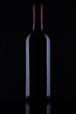 Black glass bottle of red wine on black background