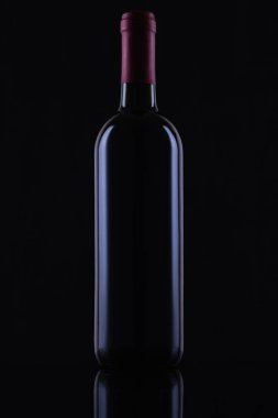 Black glass bottle of red wine on black background