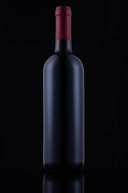 Black glass bottle of red wine on black background